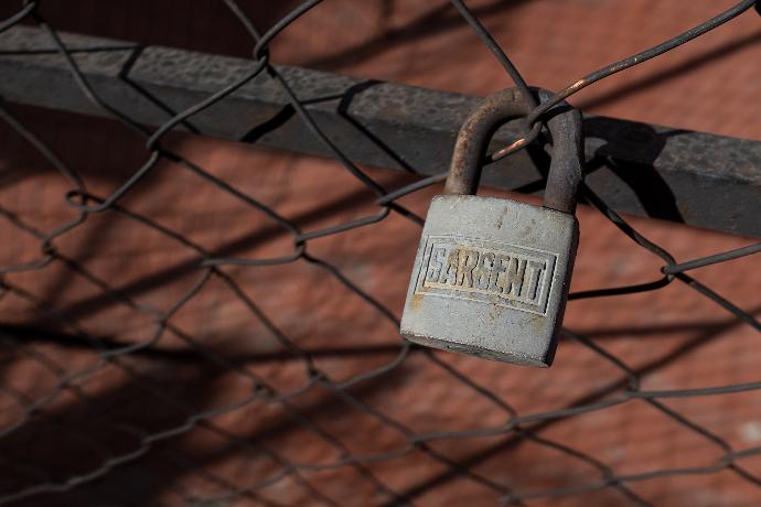 brass padlock on black metal fence